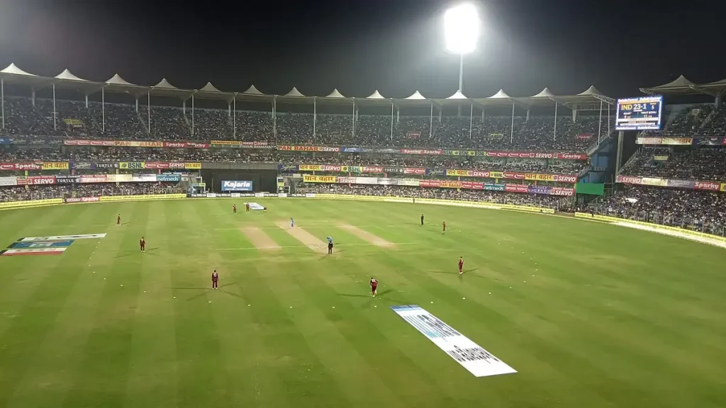 Barsapara Cricket Stadium illuminated under floodlights during an evening match in Guwahati.