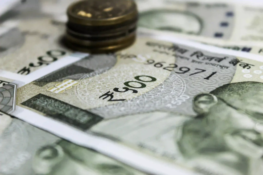 Close-up of Indian currency notes and coins illustrating Indian Rupee fall reasons and market volatility.