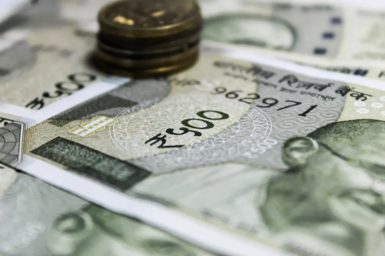 Close-up of Indian currency notes and coins illustrating Indian Rupee fall reasons and market volatility.