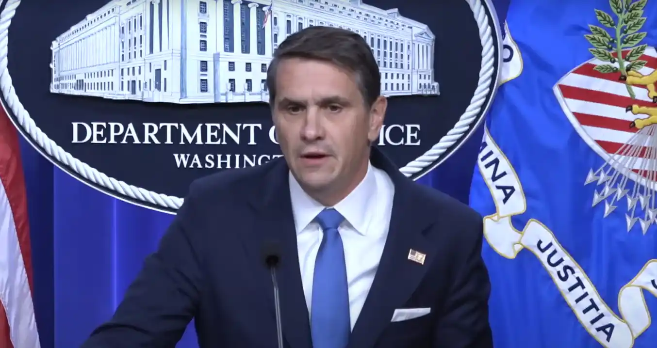An official speaks at a press briefing inside the U.S. Department of Justice with the department seal visible in the background during an announcement related to the Epstein files release.