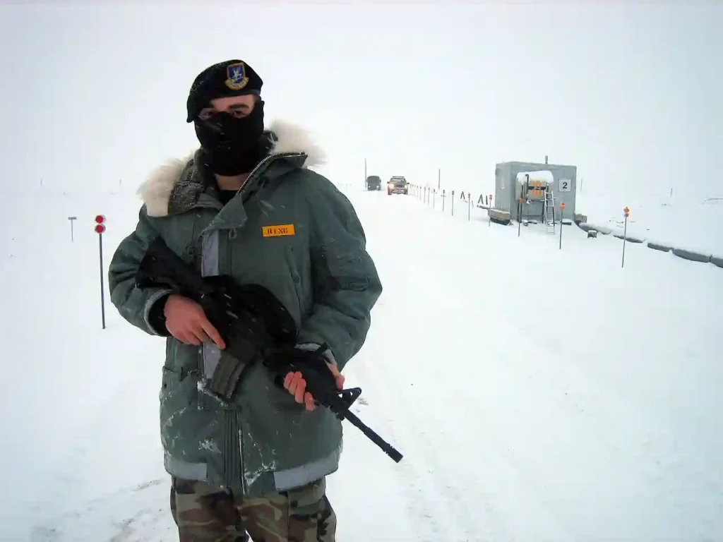 Greenland military warning context as a U.S. Air Force security forces airman patrols near Thule Air Base amid extreme Arctic conditions in Greenland.