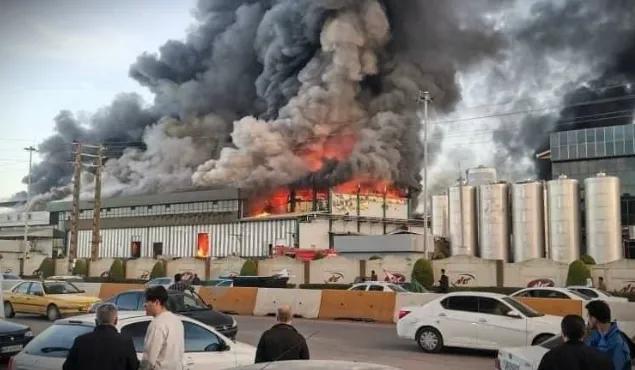 Kaleh company fire in Amol as thick black smoke and flames engulf a warehouse while emergency crews respond.