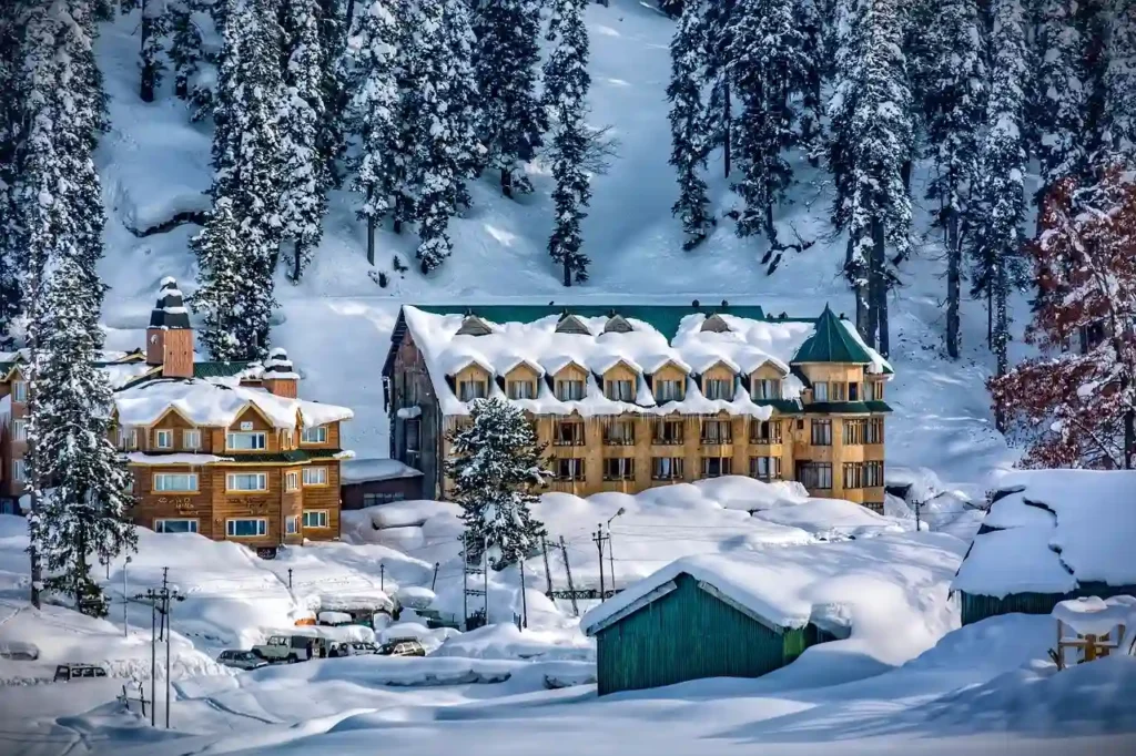 Snow-covered buildings surrounded by pine forests during intense winter conditions in Kashmir Himachal weather