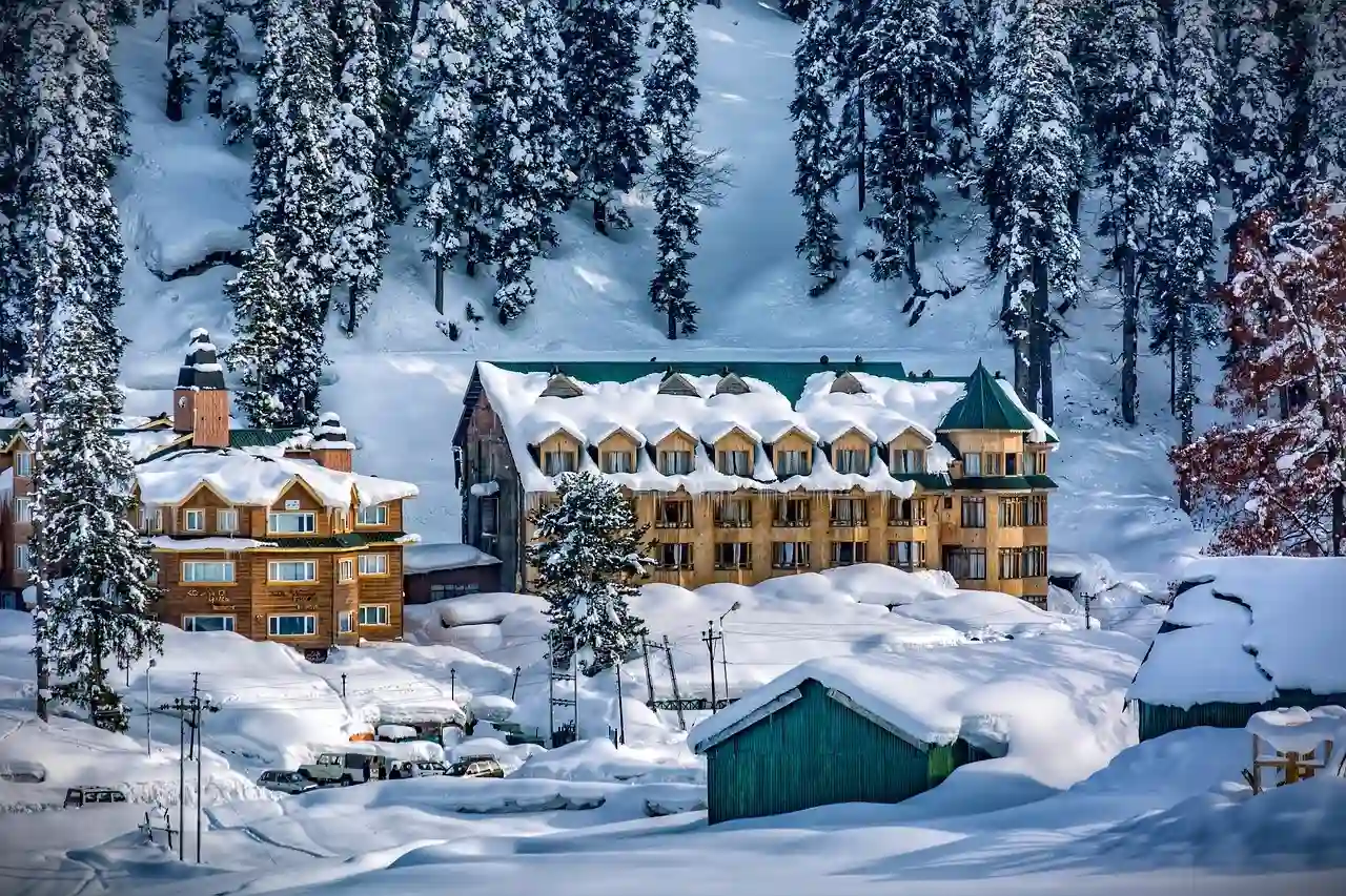 Snow-covered buildings surrounded by pine forests during intense winter conditions in Kashmir Himachal weather