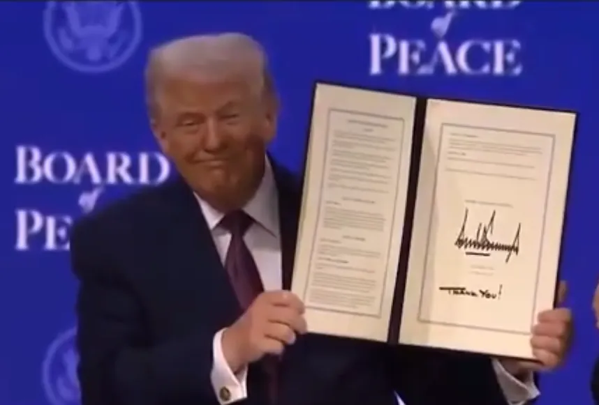 Donald Trump holds the signed document during the Trump peace charter WEF event in Davos.
