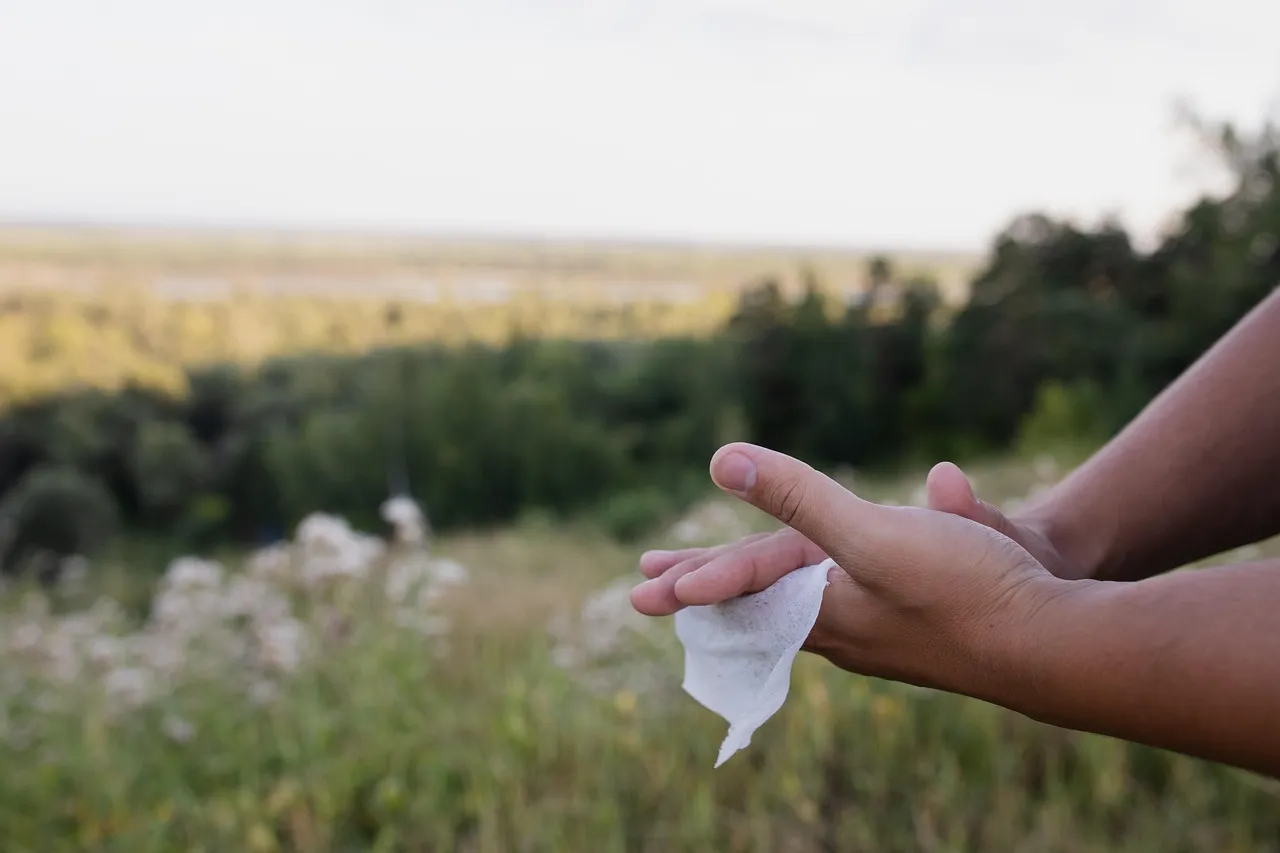 Hands holding a used wet wipe outdoors, illustrating contaminated wet wipes infection risk