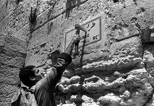 Israeli soldier removing Arabic text from a sign in East Jerusalem after the 1967 war, a historical moment shaping the Iran Israel conflict and Middle East tensions
