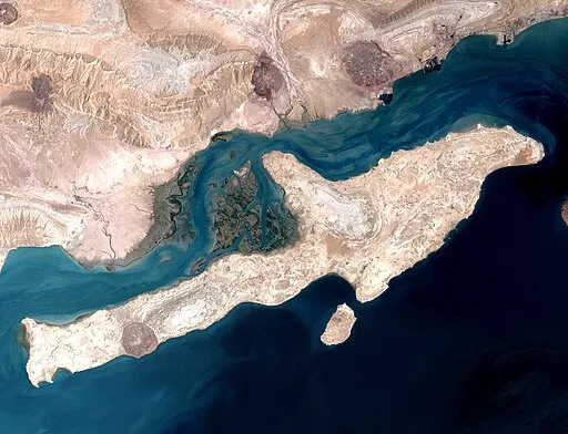 Satellite view of the Strait of Hormuz near Qeshm Island showing the critical global oil shipping chokepoint between Iran and Oman.